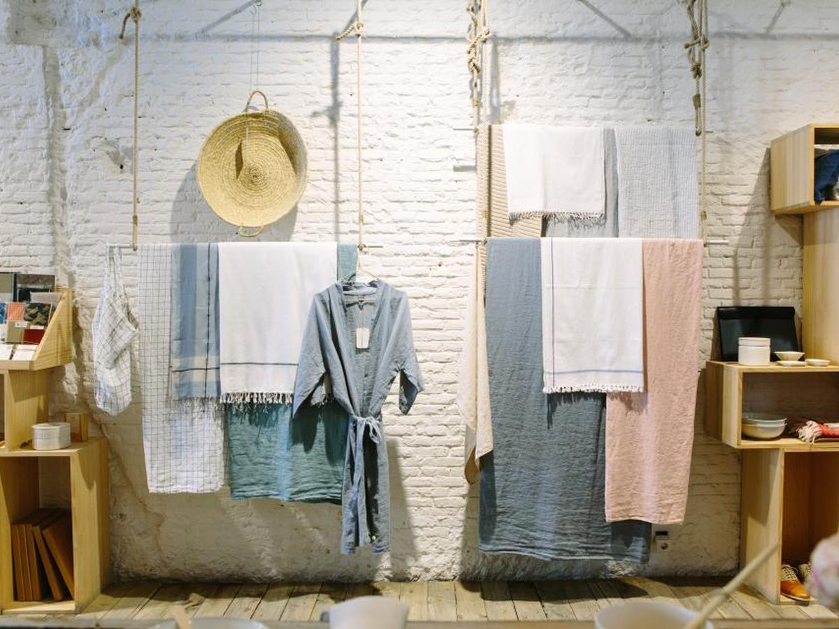 A fashion label founder checking AI-drafted product descriptions against the garment on a rack